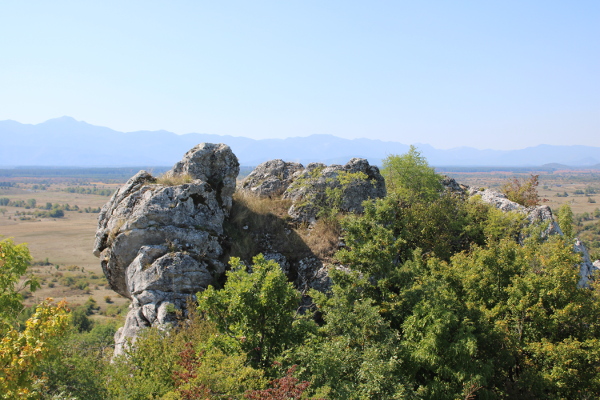 Stjenoviti vrh uzvišenja u Mogoriću na kojem se naziru neznatni ostaci srednjovjekovne utvrde Mogor grada; u pozadini su prostrano Ličko polje i planinska trupina Velebita (Foto: Goran Majetić)