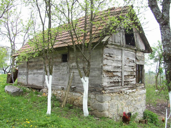 Stara seoska kuća u Vujaškovićima 2010. godine, uz koju se (lijevo) nazire manji od dva monolita, koji možda odgovara stećku stećku - sljemenjaku (Foto: Goran Majetić)