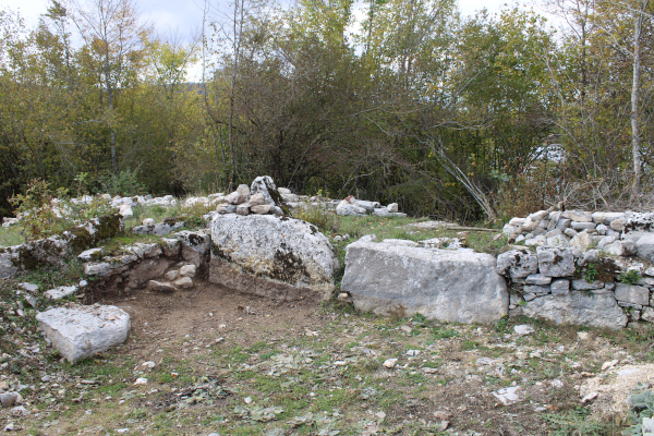 Dva velika stećka - ploče osovljena na bok i ugrađena u ogradni zid nekadašnje crkvene sjenice; na stećku na fotografiji desno uočljivi su uklesani znameni križa (lijevo) i kruga (desno dolje) (Foto: Goran Majetić)